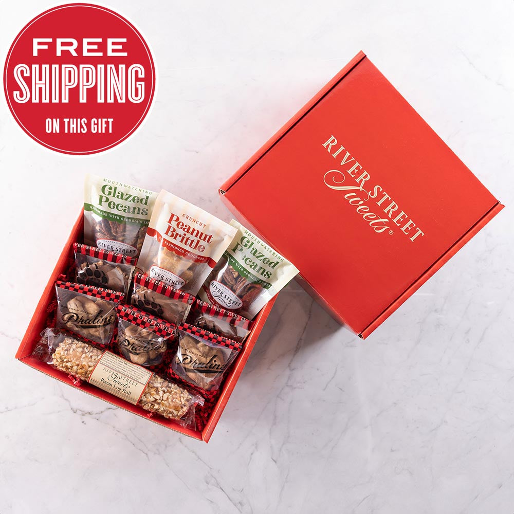 An open red gift box displaying an assortment of chocolate and nut based confectionery items, with a promotional offer of free shipping.