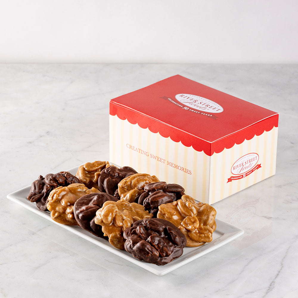 A box of chocolate and original pralines presented next to an assortment of praline sweets on a plate.