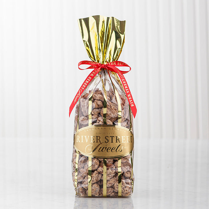 Praline pecans in a clear bag with gold stripes with a red bow