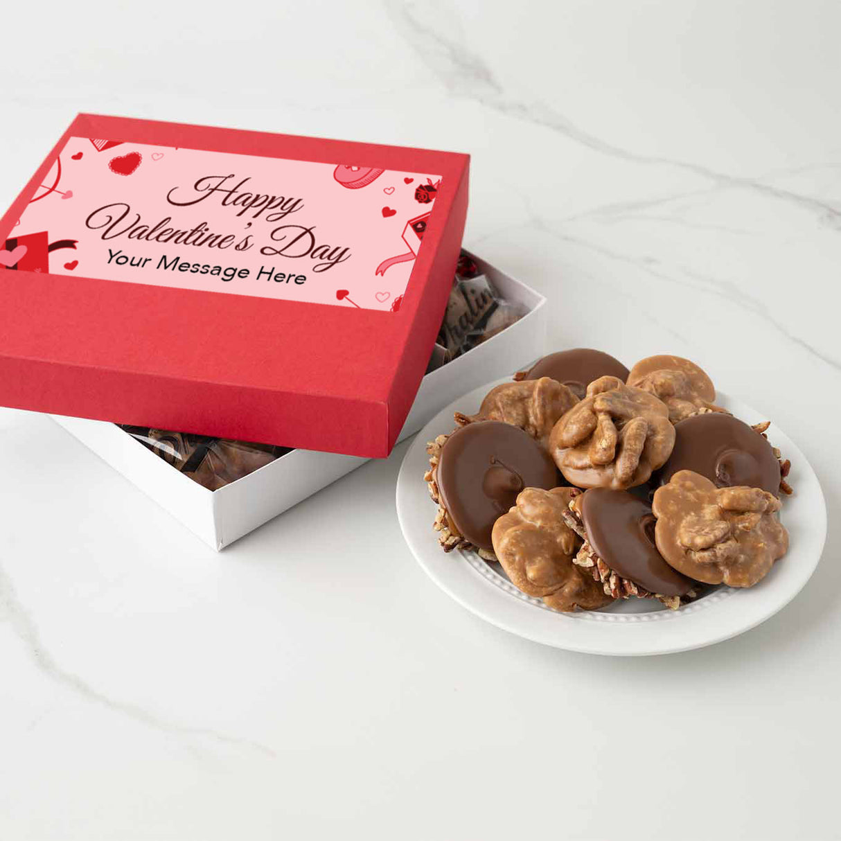 Valentine's Day themed chocolate candy box with a plate of chocolates and pralines on a white surface