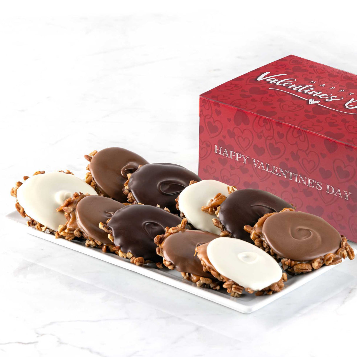 Assorted chocolate bear claws on a white plate with a Valentine's Day box in the background.