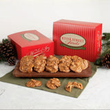 River Street Sweets, featuring red striped boxes and several pralines displayed on a wooden board with pinecones and greenery in the background.