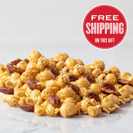 A pile of caramel nut popcorn on a white surface with a 'FREE SHIPPING ON THIS GIFT' badge in the upper right corner.