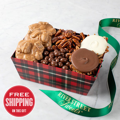 A festive plaid holiday tray filled with assorted candies including pralines, chocolate bear claws, glazed pecans, and chocolate peanuts.