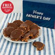 Plate of chocolate-covered treats with a Father's Day card on a striped tablecloth, featuring free shipping text.