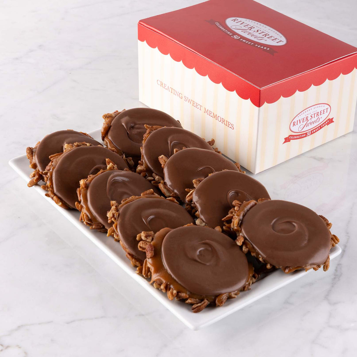 A box of Milk Chocolate Bear Claws candy displayed alongside the chocolates on a plate, with the box lid showing the brand name.