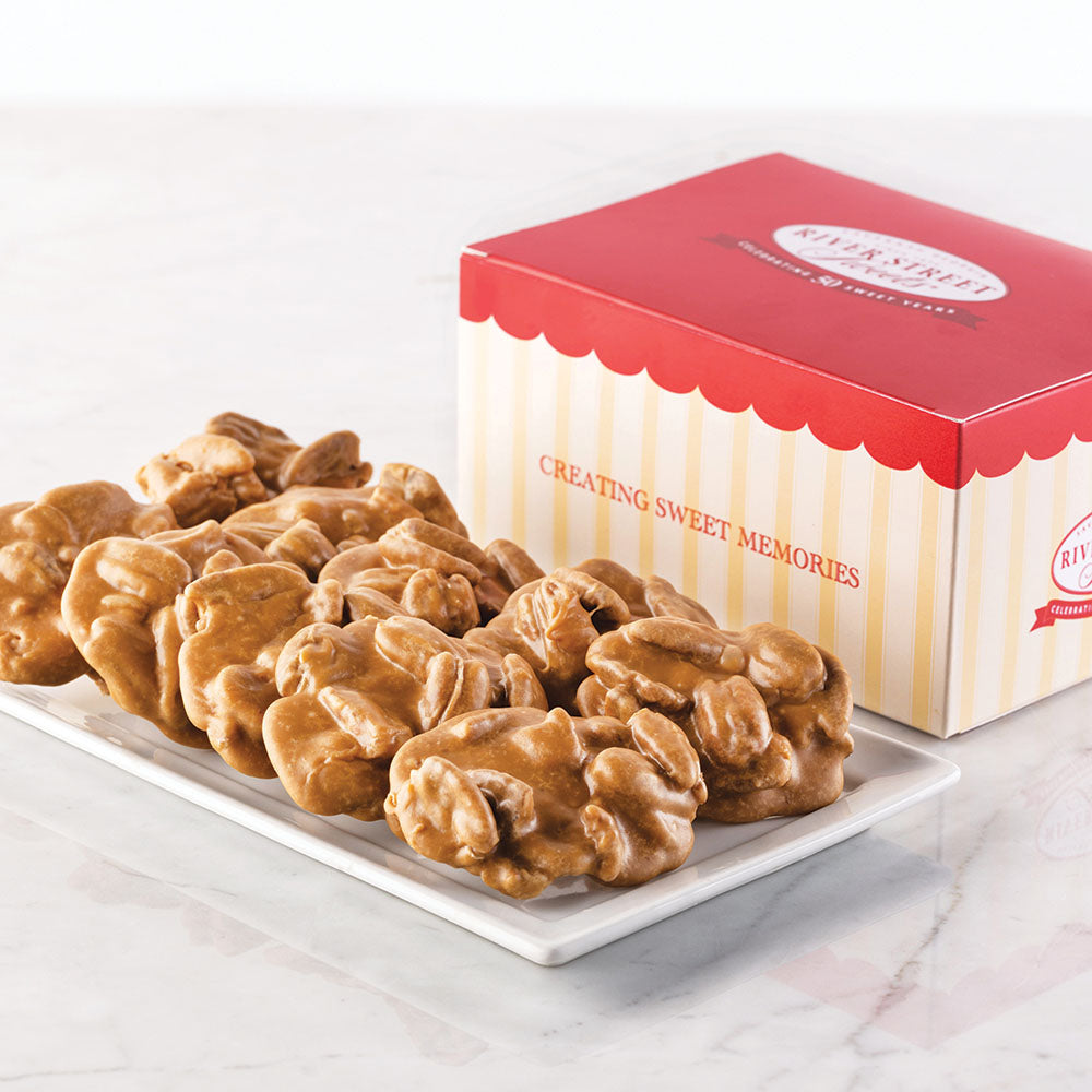 A box of Savannah's World Famous Pralines with the text 'CREATING SWEET MEMORIES' on the box. The pralines are displayed in front of the box on a white plate.
