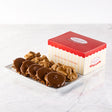 A classic gift box with red and white stripes, containing an assortment of pralines and bear claws on a marble surface.