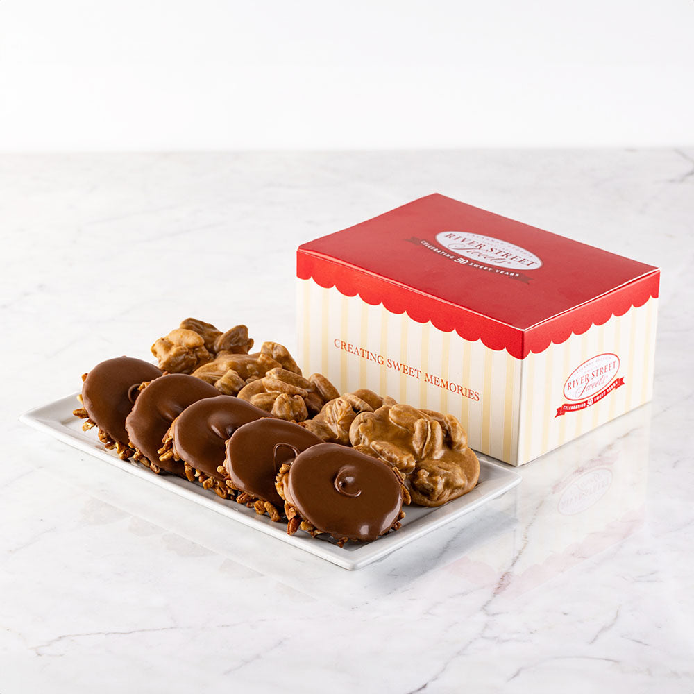 A classic gift box with red and white stripes, containing an assortment of pralines and bear claws on a marble surface.