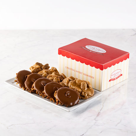 A classic gift box with red and white stripes, containing an assortment of pralines and bear claws on a marble surface.