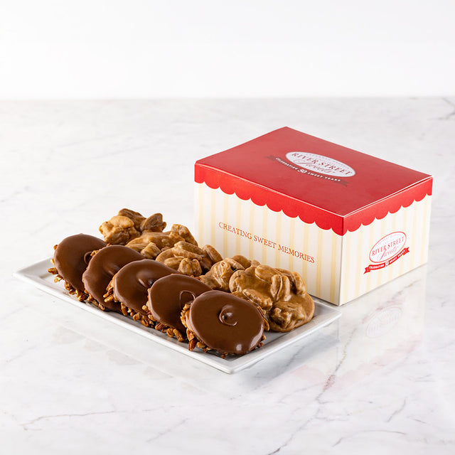 A classic gift box with red and white stripes, containing an assortment of pralines and bear claws on a marble surface.