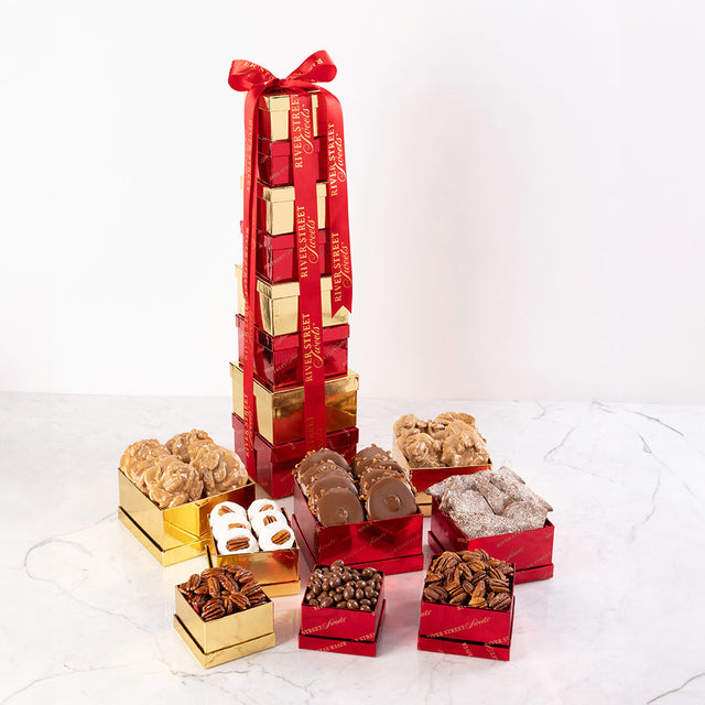 A gift tower featuring an assortment of chocolate treats including bear claws, pralines, chocolate almonds, and pecans, packaged in red and gold boxes.