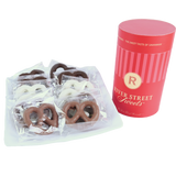 Packaged assorted pretzels on a white plate beside a red canister