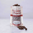 A clear plastic bag with a label reading 'Delightful Chocolate Peanuts', with some peanuts spilling out in front.