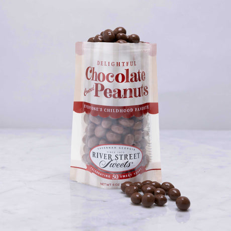 A clear plastic bag with a label reading 'Delightful Chocolate Peanuts', with some peanuts spilling out in front.