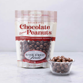 A resealable pouch of Chocolate Covered Peanuts branded as River Street Sweets, with a transparent section showing the chocolate-covered peanuts inside.