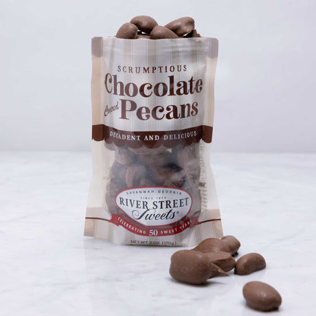 A clear plastic bag filled with chocolate covered pecans, with a label that reads 'Scrumptious Chocolate Pecans' and the brand 'River Street Sweets'.