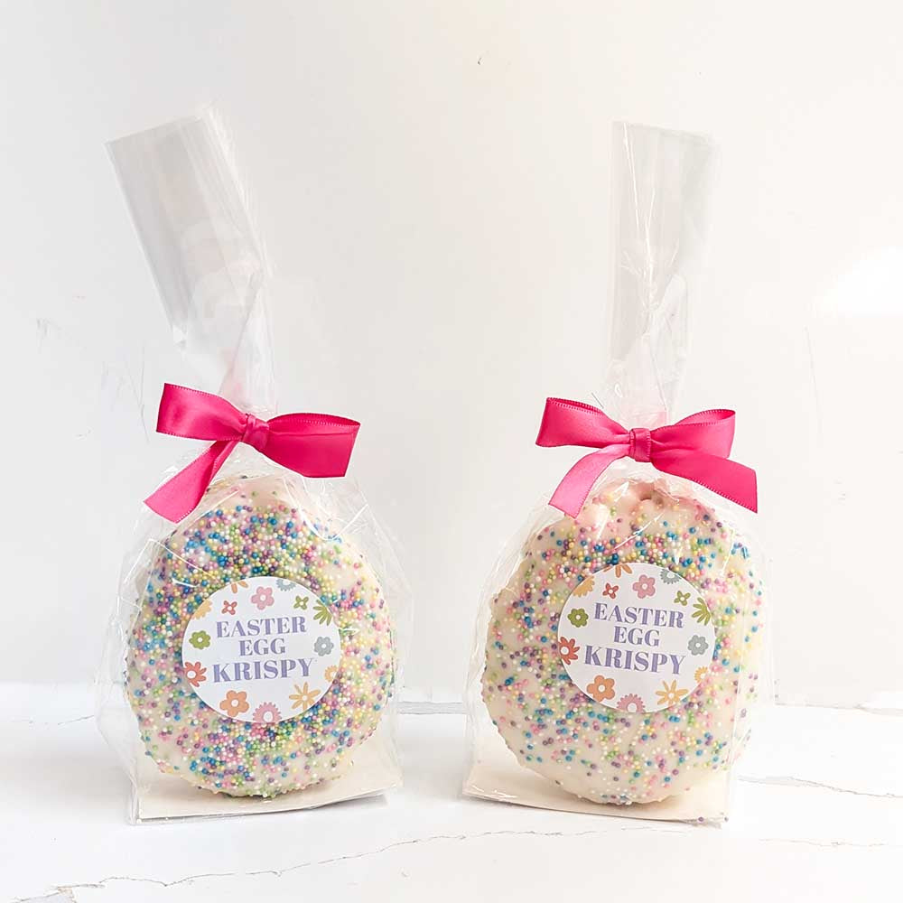 Two Easter egg-shaped Krispy treats in clear bags with pink ribbons on a white background.