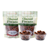Two packages of 'Glazed Pecans' from River Street Sweets with a small bowl of pecans in front.