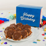 Chocolate-covered treats on a plate with a 'Happy Birthday' box in the background