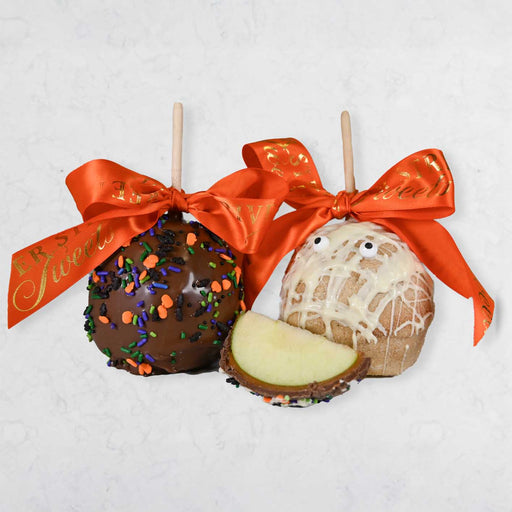 Two decorated apples on sticks with orange ribbons on a light gray background