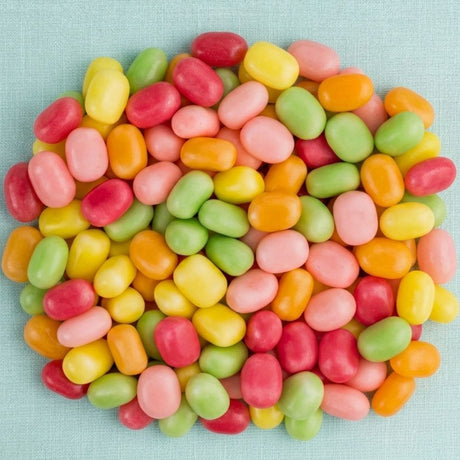 A pile of colorful Swedish candies in pink, red, yellow, orange, and green on a light blue textured background.