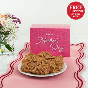 Plate of Pralines with a pink 'Happy Mother's Day' box and flowers on a white background