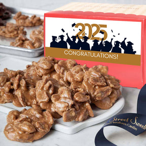A box of Savannah's World Famous Pralines with a 'Congrats Grad' label, indicating a celebration for graduation. The pralines are displayed in front on a white plate.