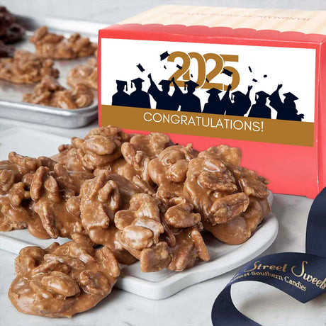 A box of Savannah's World Famous Pralines with a 'Congrats Grad' label, indicating a celebration for graduation. The pralines are displayed in front on a white plate.
