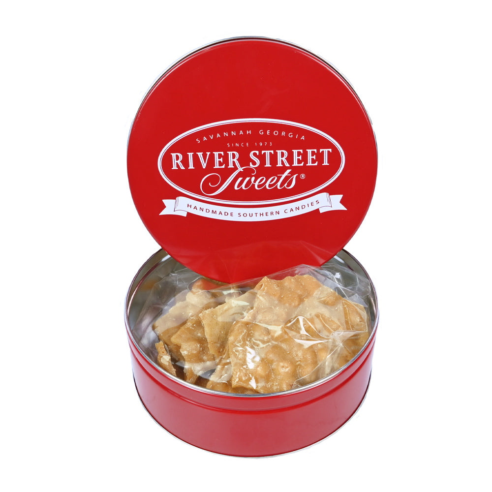 Peanut brittle in a red tin with the lid propped up on the tin