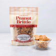 A resealable pouch of Peanut Brittle candy displayed alongside a clear bowl filled with peanut brittle pieces.
