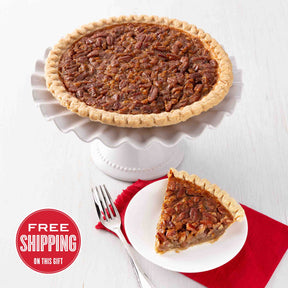 A traditional pecan pie with a slice served on a plate, placed on a white cake stand with a red napkin underneath. There is a 'Free Shipping' text overlay on the bottom left.
