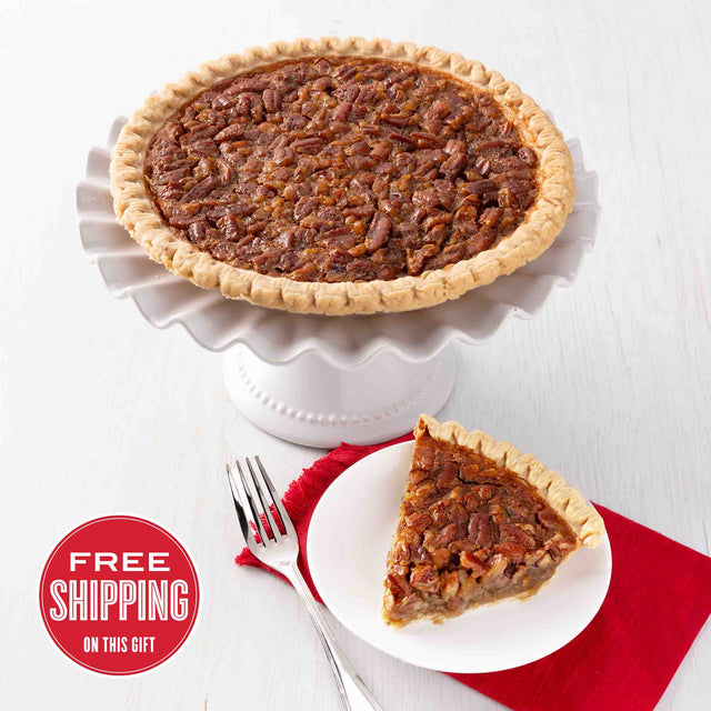 A traditional pecan pie with a slice served on a plate, placed on a white cake stand with a red napkin underneath. There is a 'Free Shipping' text overlay on the bottom left.