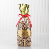 Praline pecans in a clear bag with gold stripes with a red bow