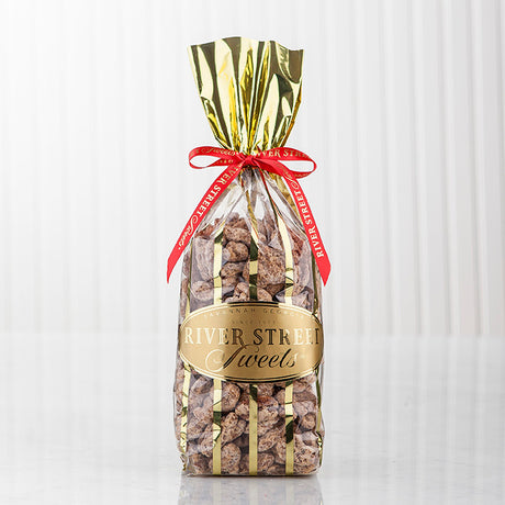 Praline pecans in a clear bag with gold stripes with a red bow