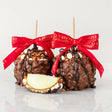 Two chocolate-dipped apples with red ribbons on a white background