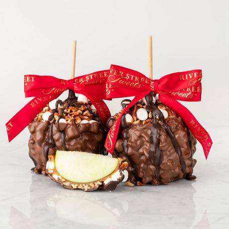 Two chocolate-dipped apples with red ribbons on a white background