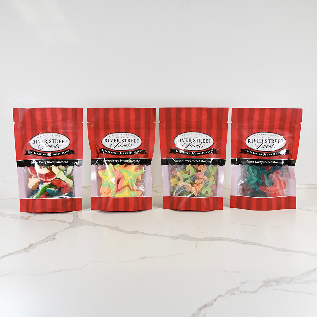 Four packages of River Street Sweets gummy bears on a white marble surface