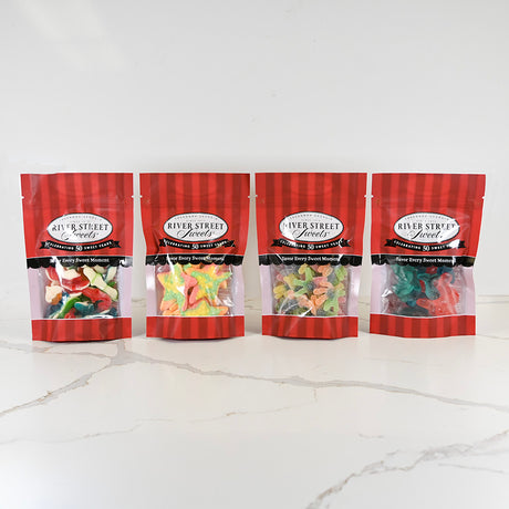Four packages of River Street Sweets gummy bears on a white marble surface