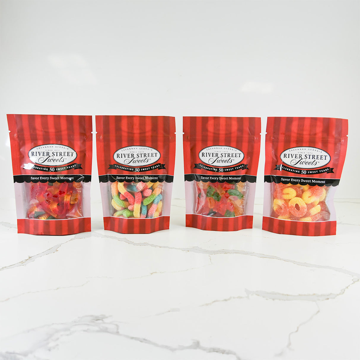 Four packages of River Street Sweets on a white marble surface