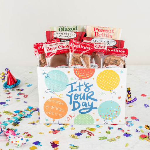 Gift box with snacks and 'It's Your Day' text on a celebratory background