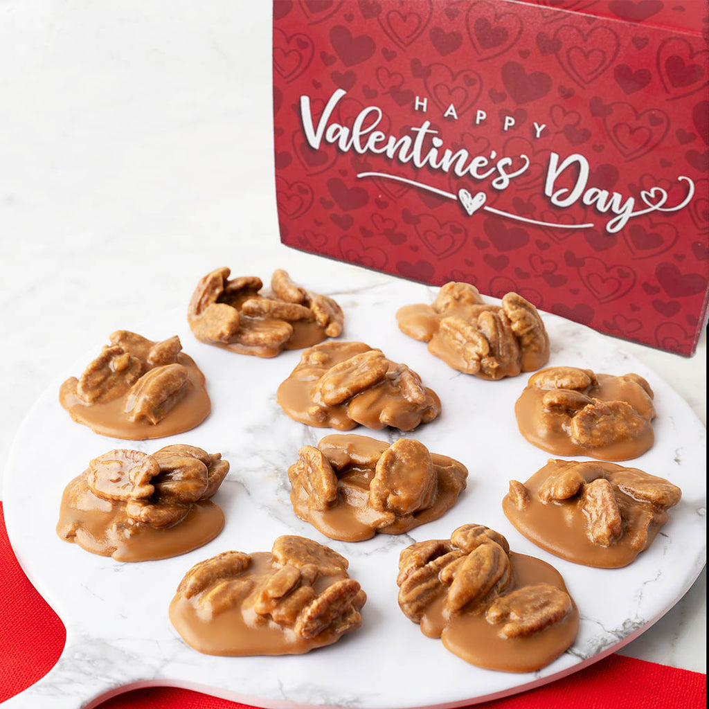 Pralines on a white plate with a red 'Happy Valentine's Day' box in the background.