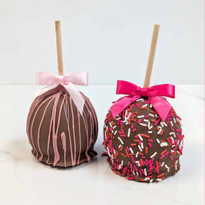 Two decorated apples with pink and white bows on a white background