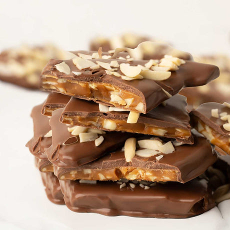 Stack of chocolate-covered almond toffee pieces on a white background