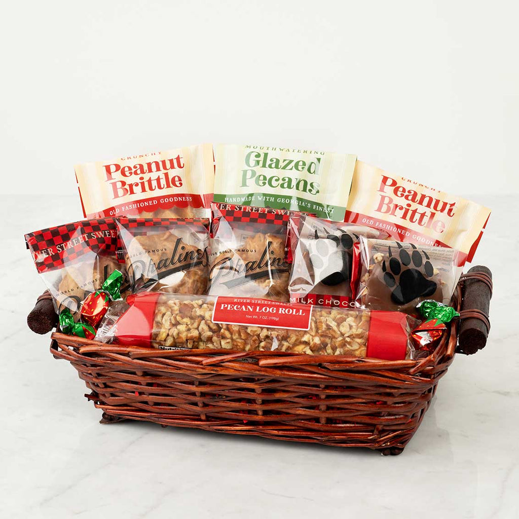 Gift basket with various treats including peanut brittle and glazed pecans on a white background