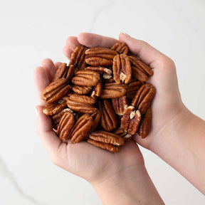 Hand holding a handful of pecans against a white background