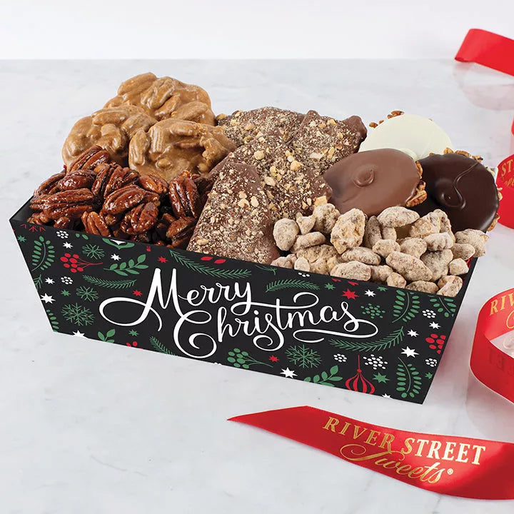 A festive holiday gift tray filled with an assortment of chocolate covered nuts and confectionery treats, including pralines and bear claws, with a 'Merry Christmas' message on the packaging.