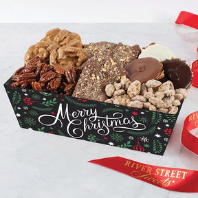A festive holiday gift tray filled with an assortment of chocolate covered nuts and confectionery treats, including pralines and bear claws, with a 'Merry Christmas' message on the packaging.
