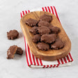 A wooden board with bear claw bites with pecans on a red and white striped napkin.