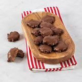 A wooden board with bear claw bites with pecans on a red and white striped napkin.